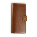 Mustard brown top-grain leather checkbook cover, closed and laid flat. Smooth pull-up surface with warm honey tones and natural character marks. Hand-stitched edges in matching thread with a small antique brass snap closure tab on the right side.