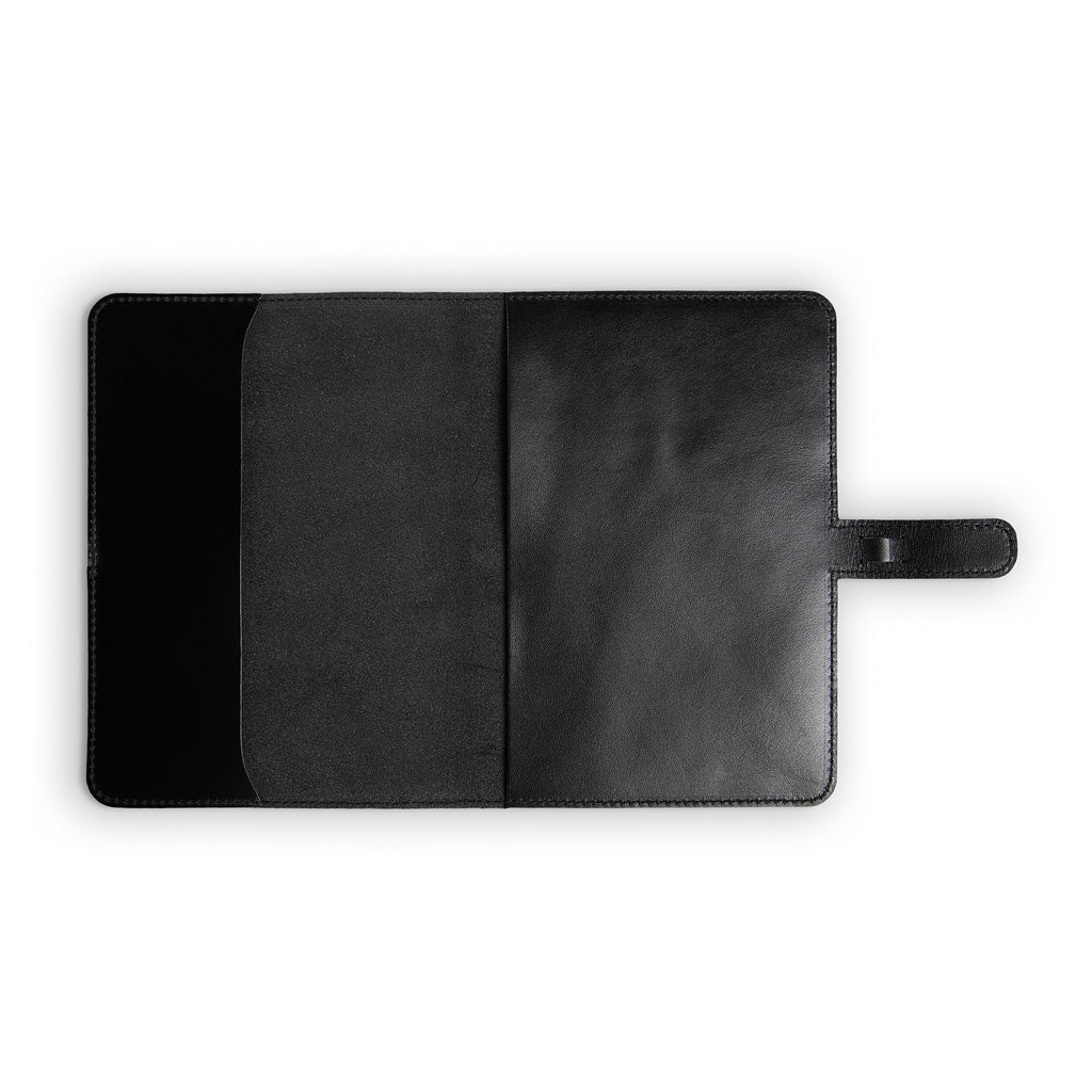 Interior of black DuPage leather journal fully open and empty, showing pull-up Dexios calfskin lining on both panels, slip pocket on left, black stitching, and strap tab on right.