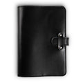 Black Dexios pull-up calfskin leather journal, front cover view, with black saddle stitching along edges and a leather strap closure secured by two silver-tone rivets on the right side.