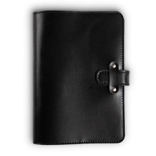 Black Dexios pull-up calfskin leather journal, front cover view, with black saddle stitching along edges and a leather strap closure secured by two silver-tone rivets on the right side.