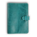 Turquoise green Laodamas buffalo leather journal, front cover view, showing distressed pull-up surface with bold natural grain and tonal variation, cream saddle stitching, and antique brass rivet strap closure.