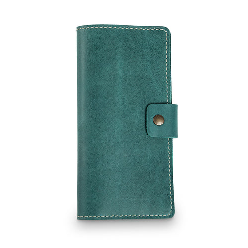 Turquoise green top-grain buffalo leather checkbook cover, closed and laid flat. Matte pull-up surface with fine natural grain texture and subtle tonal variation. Hand-stitched edges in contrasting cream thread with an antique brass snap closure tab on the right side.