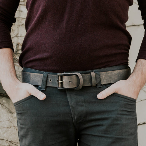 Man wearing a rustic brown handcrafted leather belt with dark trousers and burgundy sweater