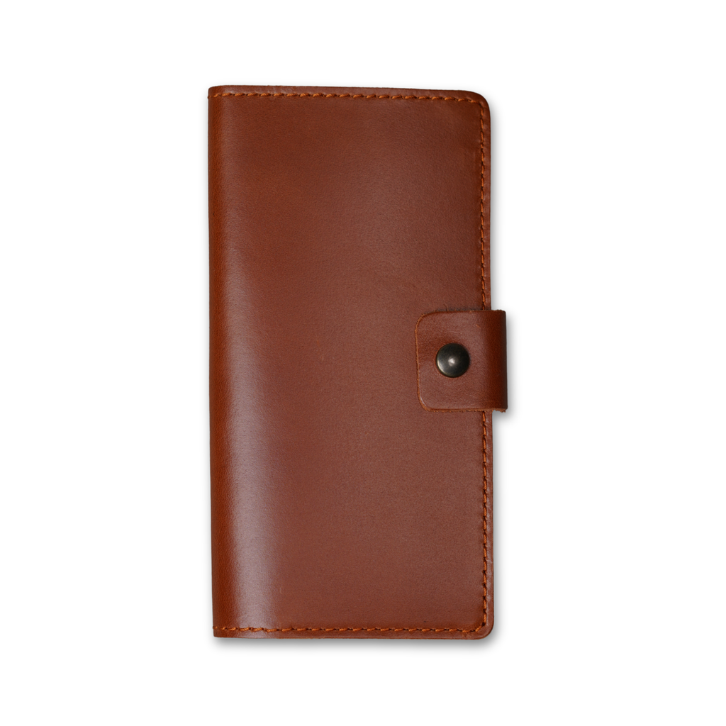 Clark Leather Checkbook Cover in Dual Tone Whiskey, closed on white. DT Lux cowhide in warm whiskey tan with glossy pull-up finish and tonal depth. Warm tonal saddle stitching on all edges. Antique brass snap tab on right.