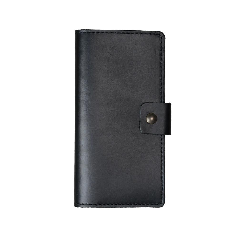 Clark Leather Checkbook Cover in Dual Tone Black, closed and laid flat on a white surface. DT Lux cowhide in a deep black with a glossy pull-up finish showing subtle tonal variation where the leather bends and catches light. Tonal dark saddle stitching runs along all four edges. A small leather tab with an antique brass snap closure sits centered on the right edge.