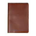 Dual tone whiskey leather passport cover, closed and laid flat. Warm cognac brown glossy pull-up surface with bright amber tonal variation. Hand-stitched edges in matching burnt orange thread. Rounded corners and clean minimal silhouette with no hardware or closures.