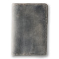 Rock gray crazy horse calfskin passport cover, closed and laid flat. Matte waxy surface with natural tonal variation shifting from dark charcoal to lighter gray. Hand-stitched edges in matching gray thread. Rounded corners and clean minimal silhouette with no hardware or closures.