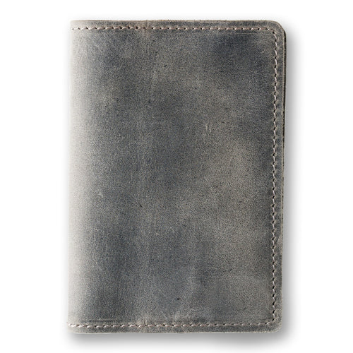 Rock gray crazy horse calfskin passport cover, closed and laid flat. Matte waxy surface with natural tonal variation shifting from dark charcoal to lighter gray. Hand-stitched edges in matching gray thread. Rounded corners and clean minimal silhouette with no hardware or closures.