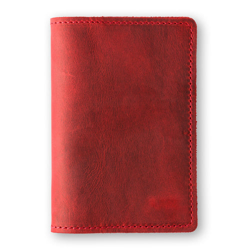 Rose red crazy horse calfskin passport cover, closed and laid flat. Vibrant waxy surface with deep crimson tonal variation and natural character marks throughout. Hand-stitched edges in matching red thread. Rounded corners and clean minimal silhouette with no hardware or closures.