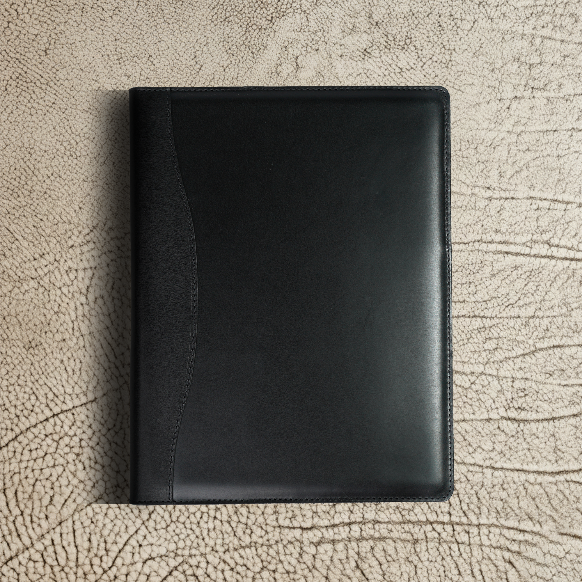 Marshall Leather Legal Padfolio closed and resting on a textured surface. Sleek, professional design in Djor Black full-grain leather—made for quiet confidence in every meeting.