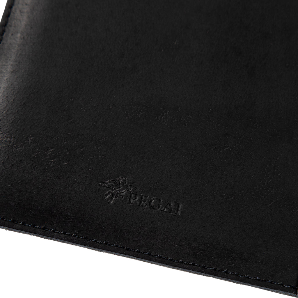Close-up of charcoal black Iphitos buffalo leather on PEGAI Eriksen Jr. padfolio, showing embossed PEGAI pegasus logo and tonal edge stitching detail.