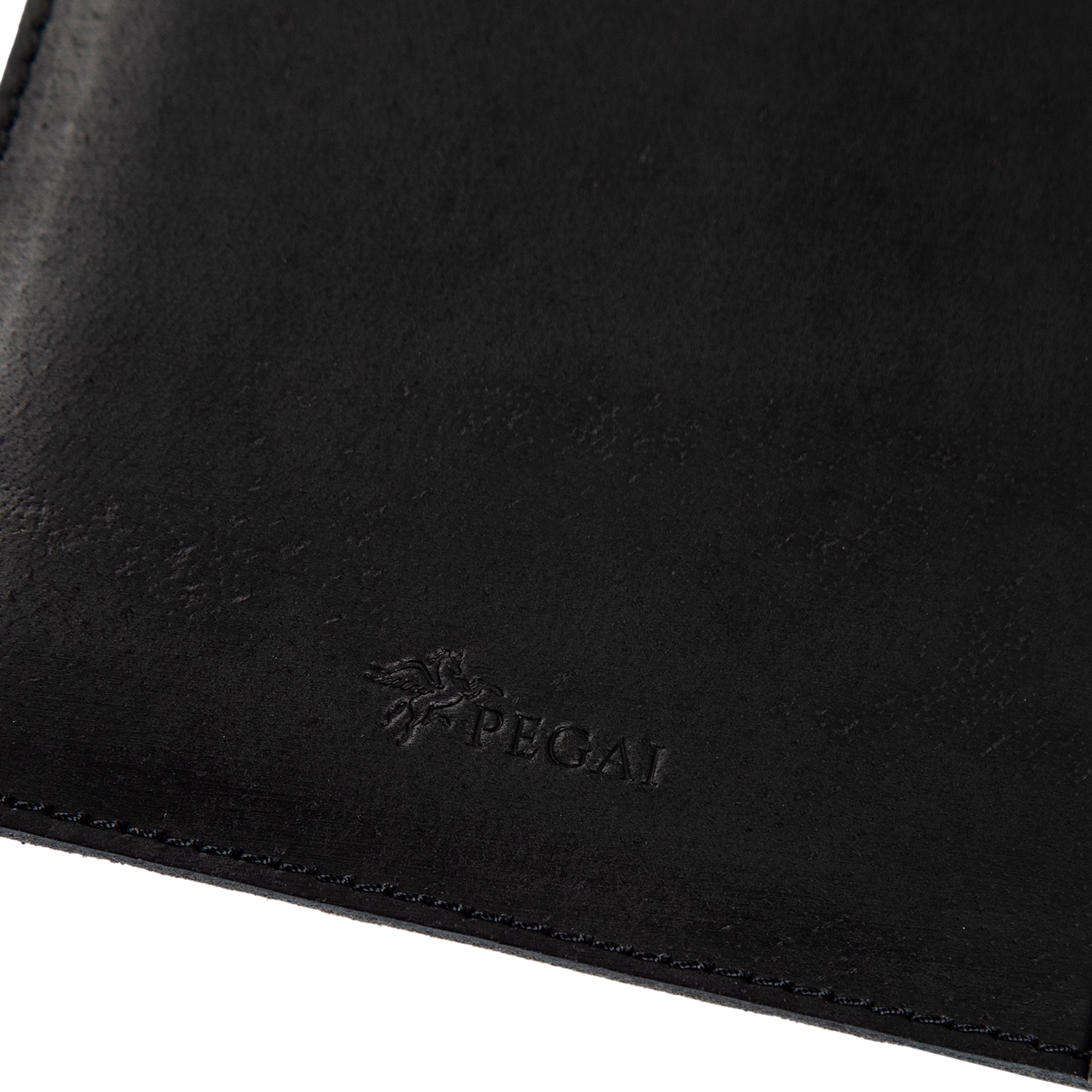 Close-up of charcoal black Iphitos buffalo leather on PEGAI Eriksen Jr. padfolio, showing embossed PEGAI pegasus logo and tonal edge stitching detail.