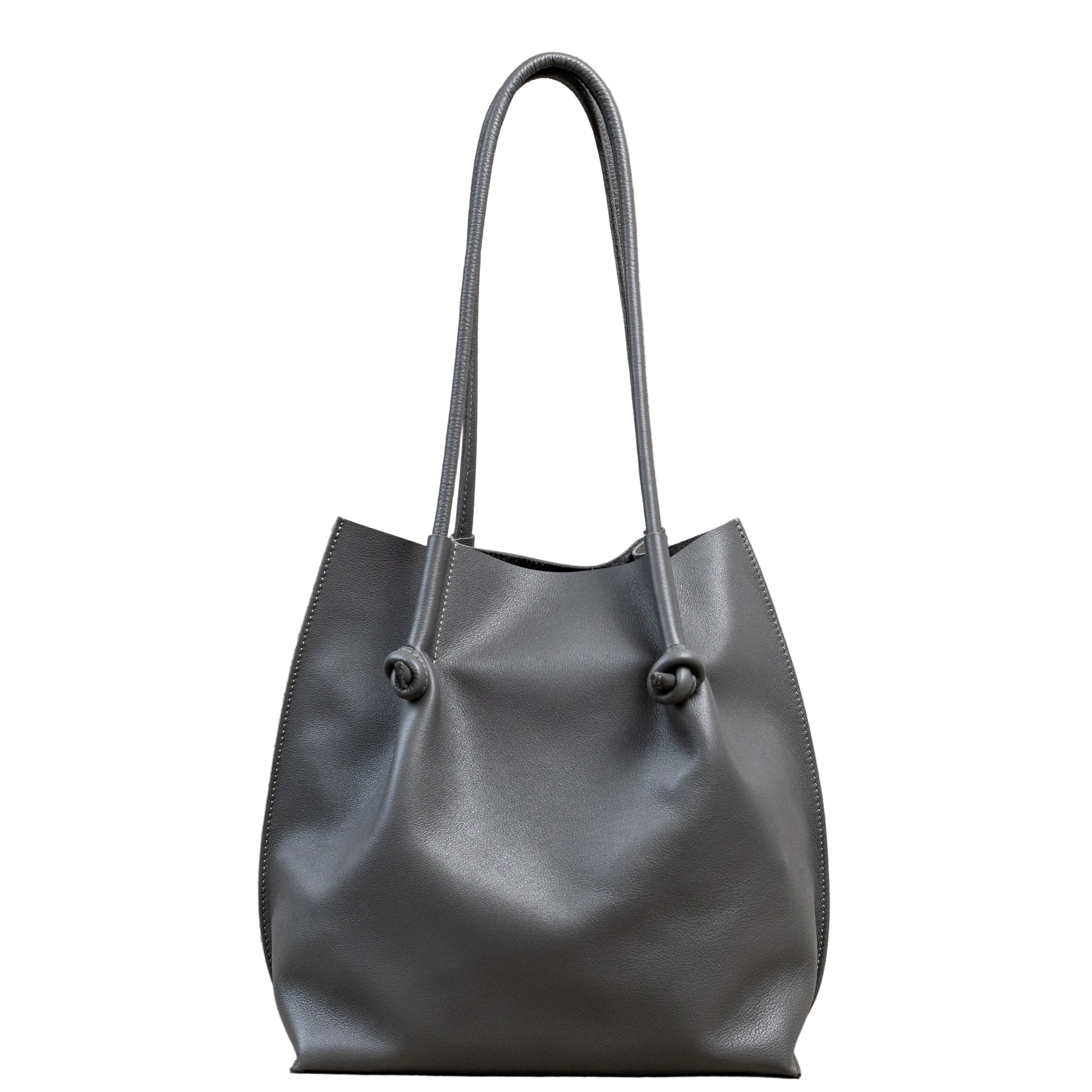 Flora Everyday Tote in Silky Calf Gray stands upright with a smooth, fine-grain finish, dual rolled handles, and a single knotted leather closure on each side.
