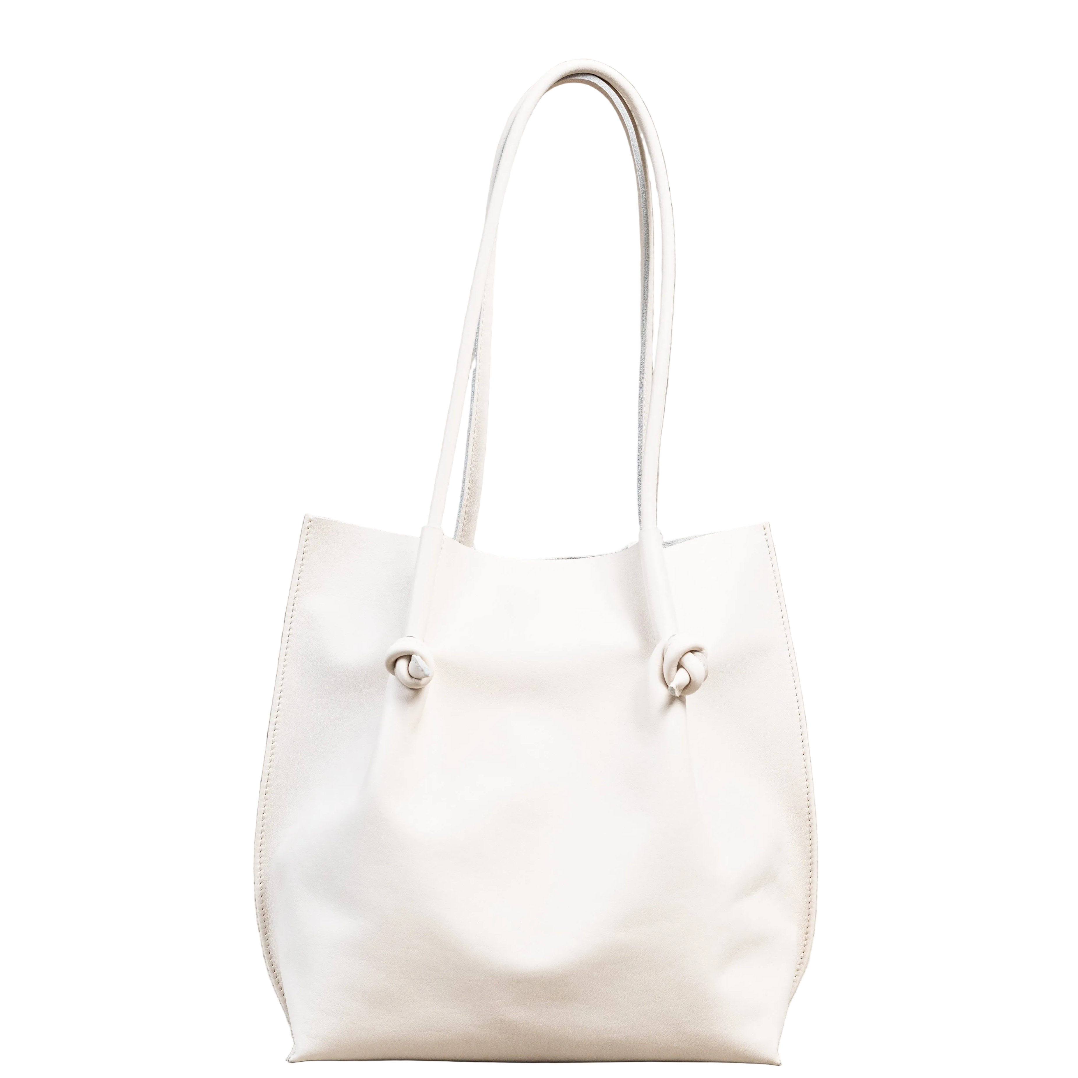Flora Everyday Tote in Smooth Calf Cream stands upright with a soft, fine-grain finish, dual rolled handles, and a single knotted leather closure on each side.
