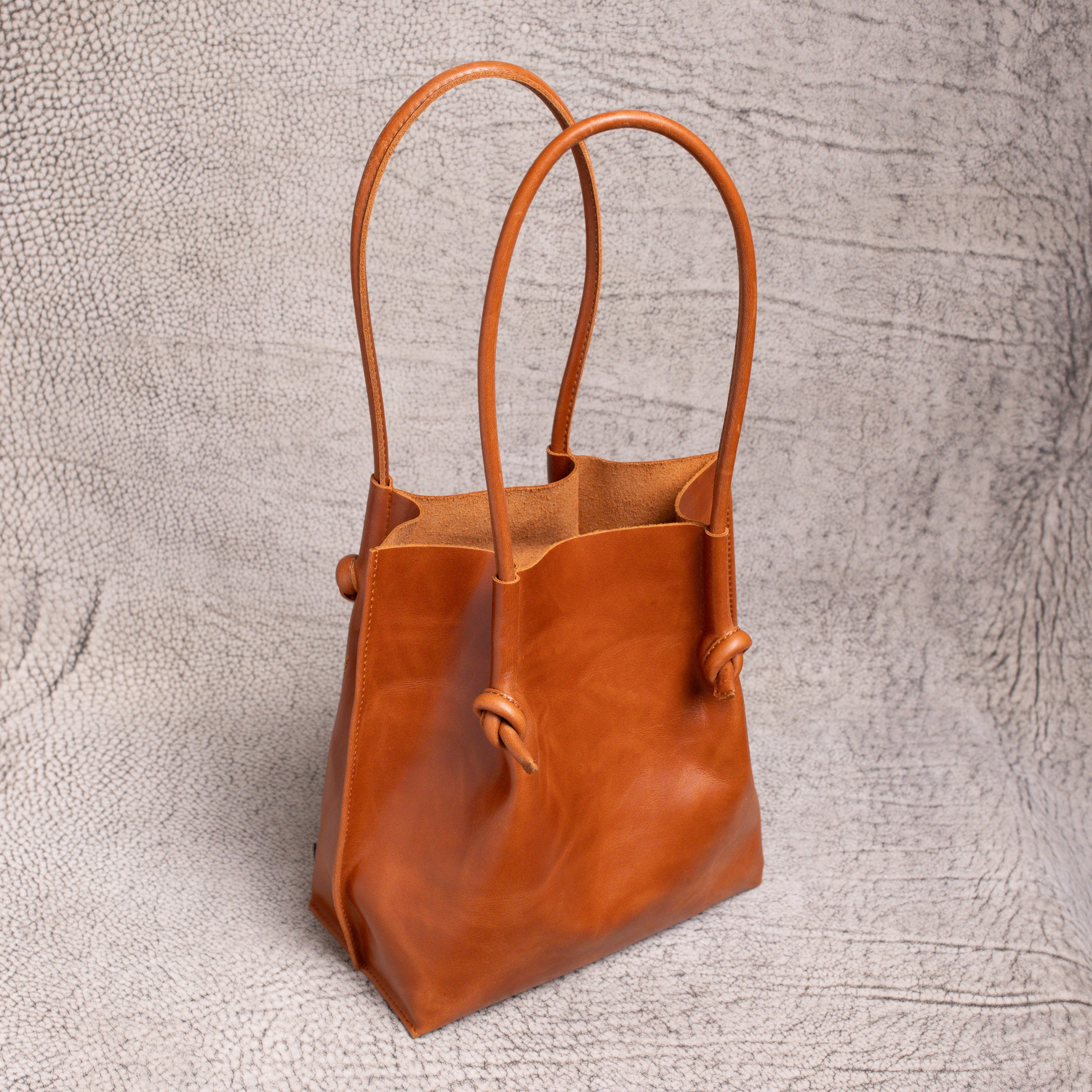 Angled side view of the Flora Everyday Leather Tote, highlighting its spacious open-top design and soft suede interior.