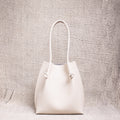 Flora Everyday Tote in Togo Beige leather standing upright on a textured surface.