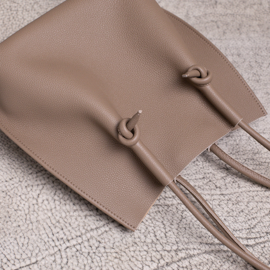 Overhead flat lay showing the top handles and relaxed body of the Flora Tote in warm Etoupe calfskin.