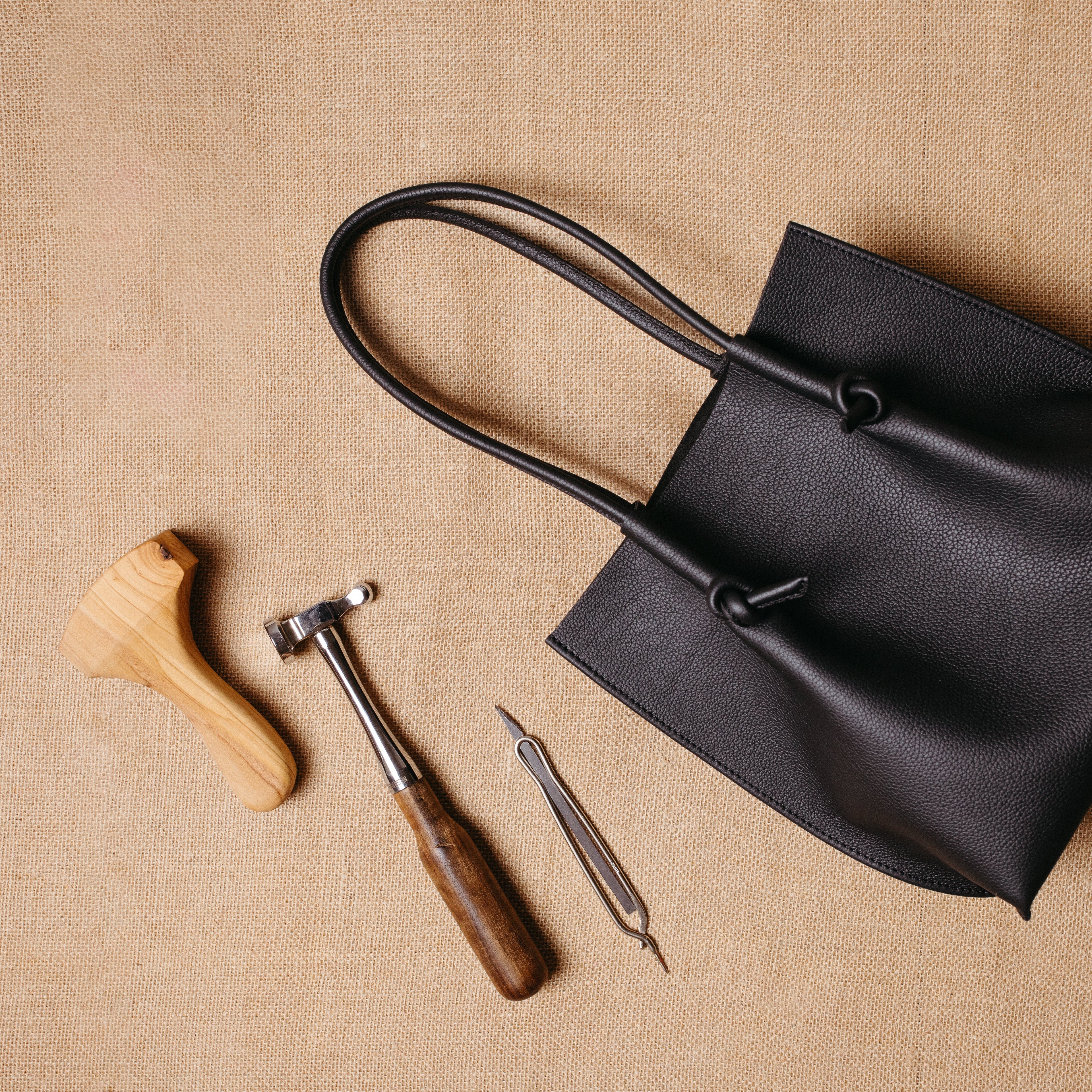 Flat lay of the Flora tote alongside traditional leather tools, visually connecting artisanal craftsmanship to the final product.