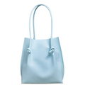 Flora Everyday Tote in Silky Calf Sky stands upright with a smooth, fine-grain finish, dual rolled handles, and a single knotted leather closure on each side.