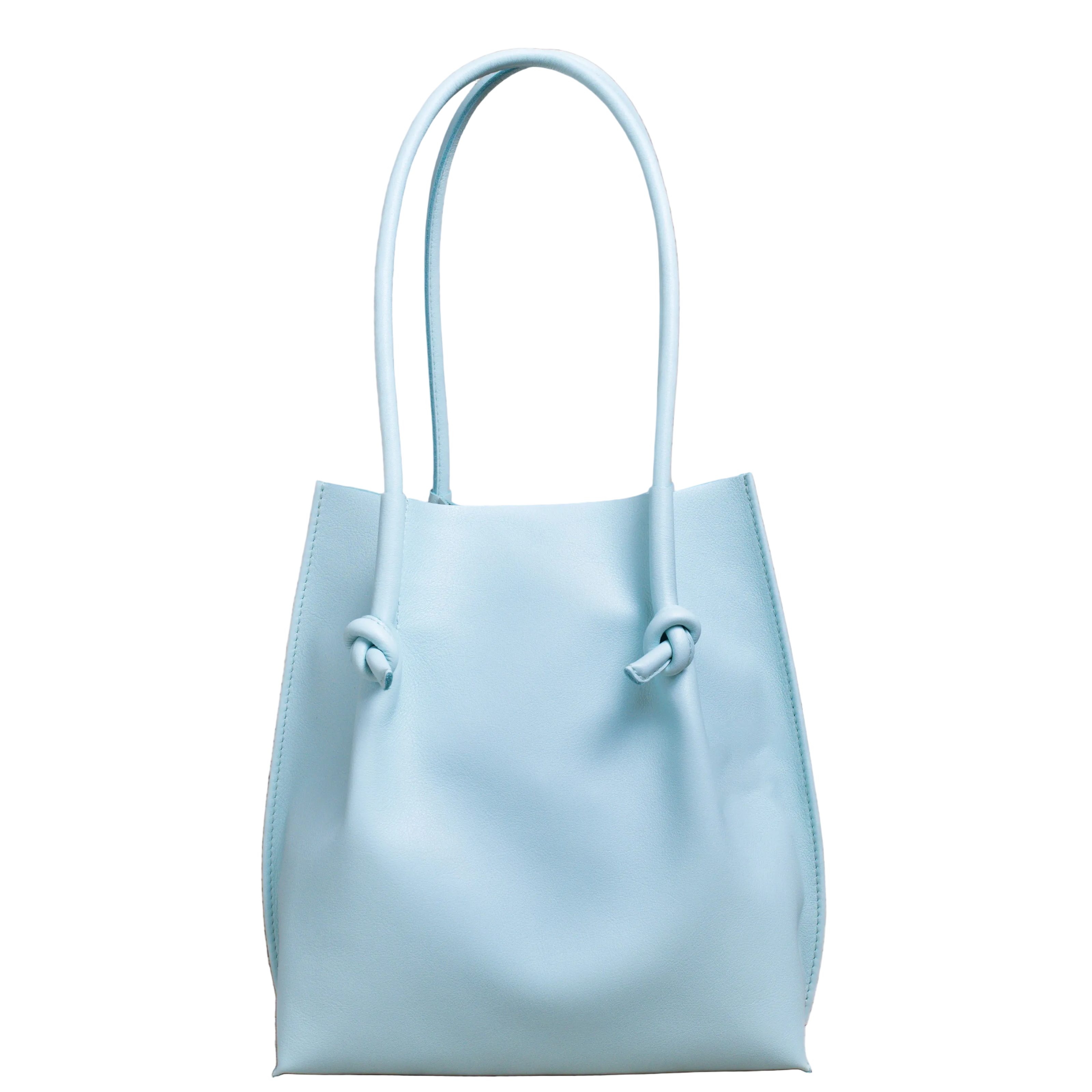 Flora Everyday Tote in Silky Calf Sky stands upright with a smooth, fine-grain finish, dual rolled handles, and a single knotted leather closure on each side.