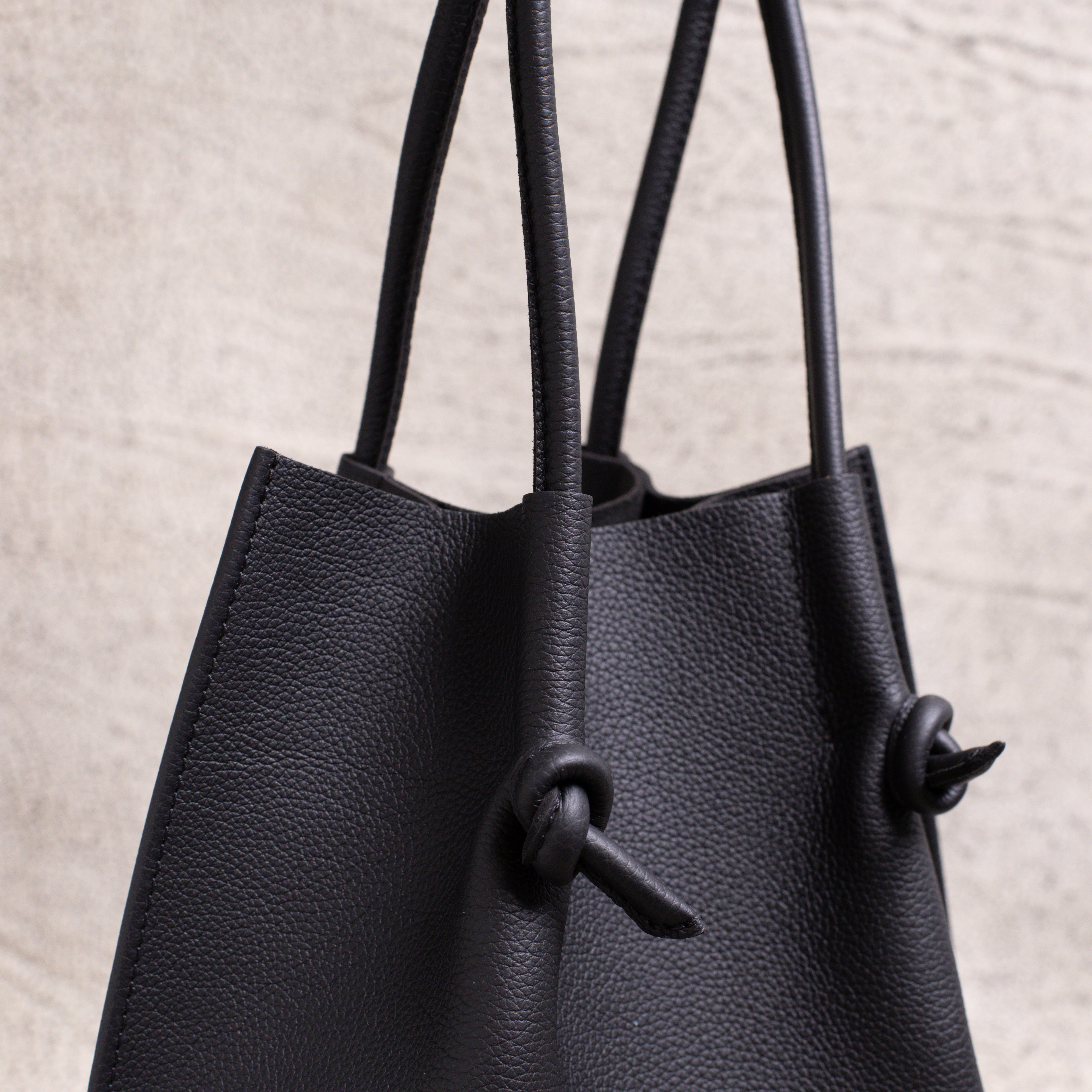 Side detail shot of the tote’s handles and folded-edge design, reflecting durability and minimalist elegance.