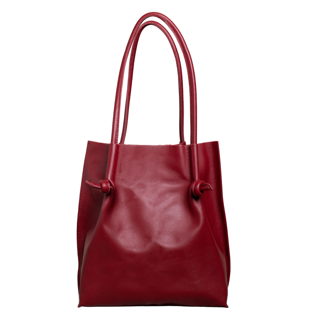 Flora Everyday Tote in Smooth Calf Burgundy stands upright with a soft, fine-grain finish, dual rolled handles, and a single knotted leather closure on each side.
