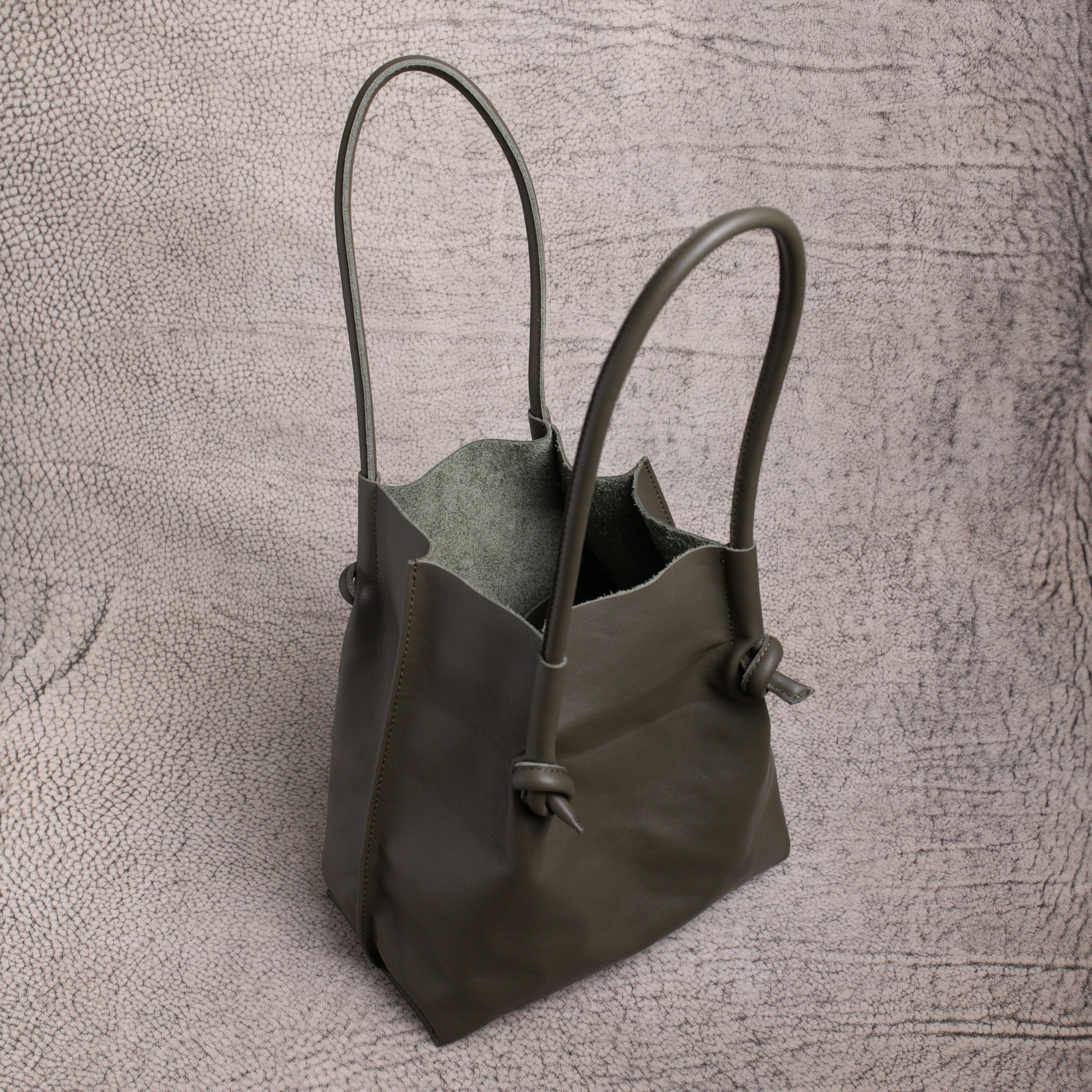 Top-down look inside the Flora Leather Tote in Smooth Calf Green, revealing its raw suede interior and spacious, open-top design.