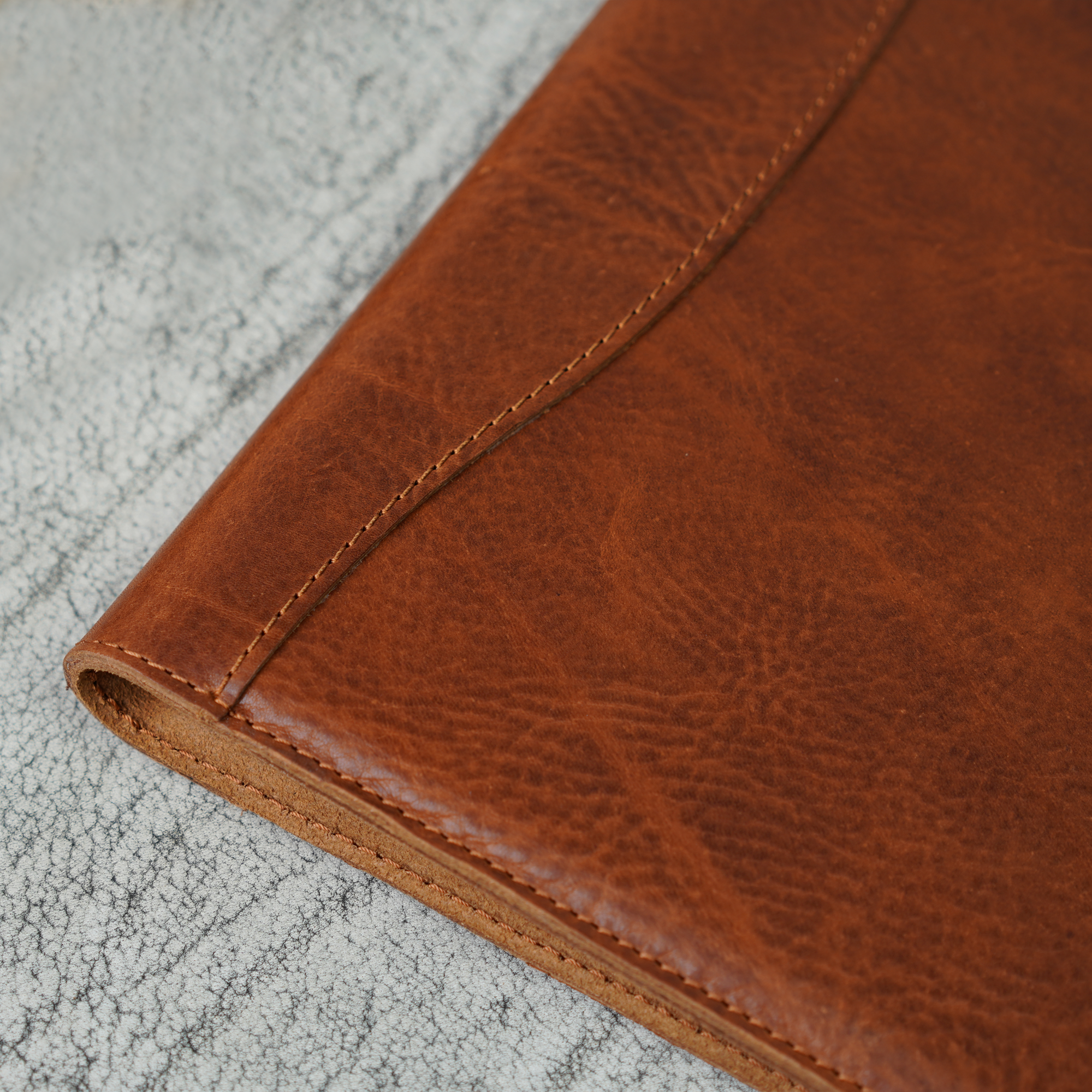 Close-up of the spine and stitching on the Missouri Dark Brown Marshall Padfolio. Highlights the warmth and texture of full-grain leather, stitched by hand with care for timeless durability and understated style.