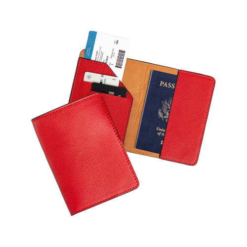 Two red leather passport wallets on gray: one closed showing the vibrant pebbled exterior, one open with diagonal card pocket holding two cards and a boarding pass on the left, and a U.S. passport inserted on the right. Warm cognac tan lining and tonal red stitching throughout.