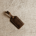 Rich brown full-grain leather luggage tag with brass buckle, perfect for gifting or upgrading your travel essentials.