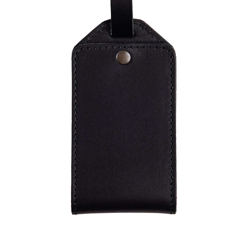 Close-up of black full-grain leather luggage tag with snap closure and fine stitching