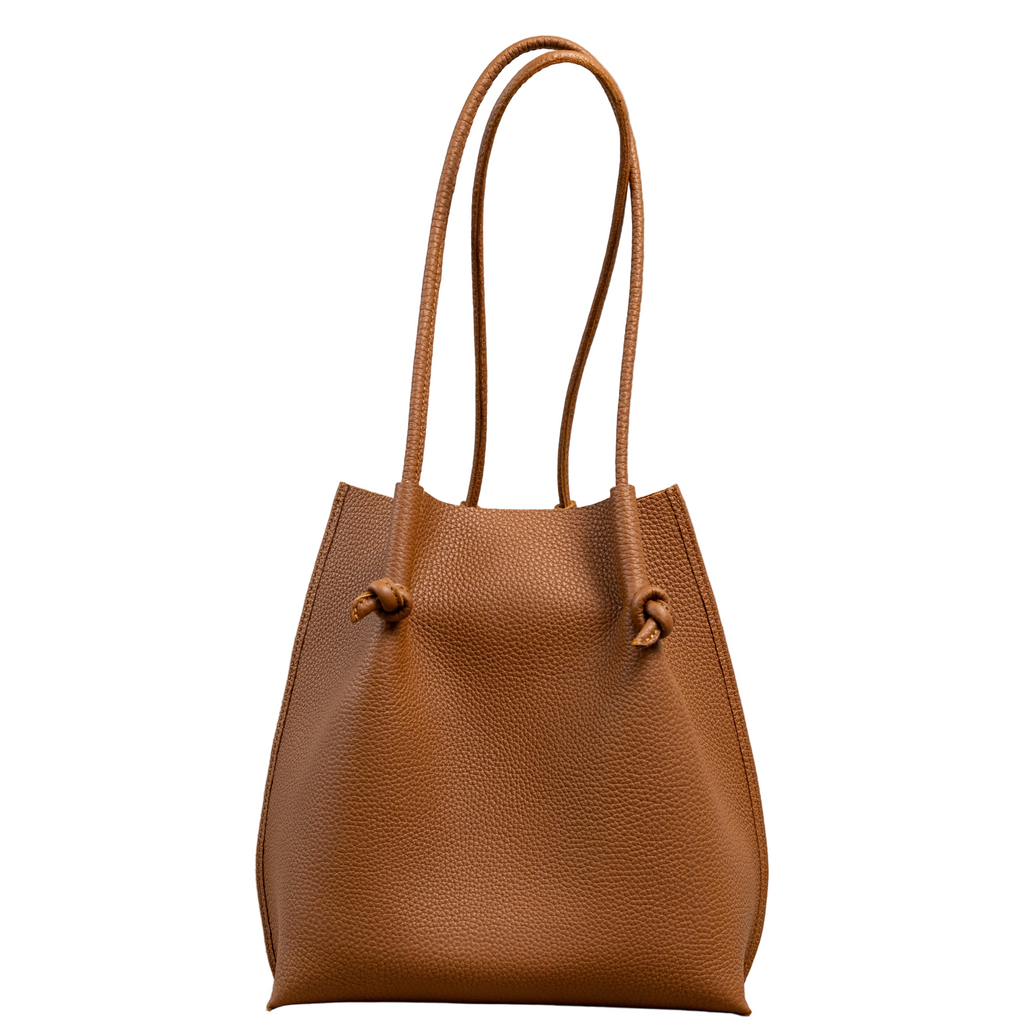 Flora Everyday Leather Tote in Togo Calf Taba, front view on white background. Structured bucket-style tote with tall rolled leather handles and two knotted leather ties cinching the open top.