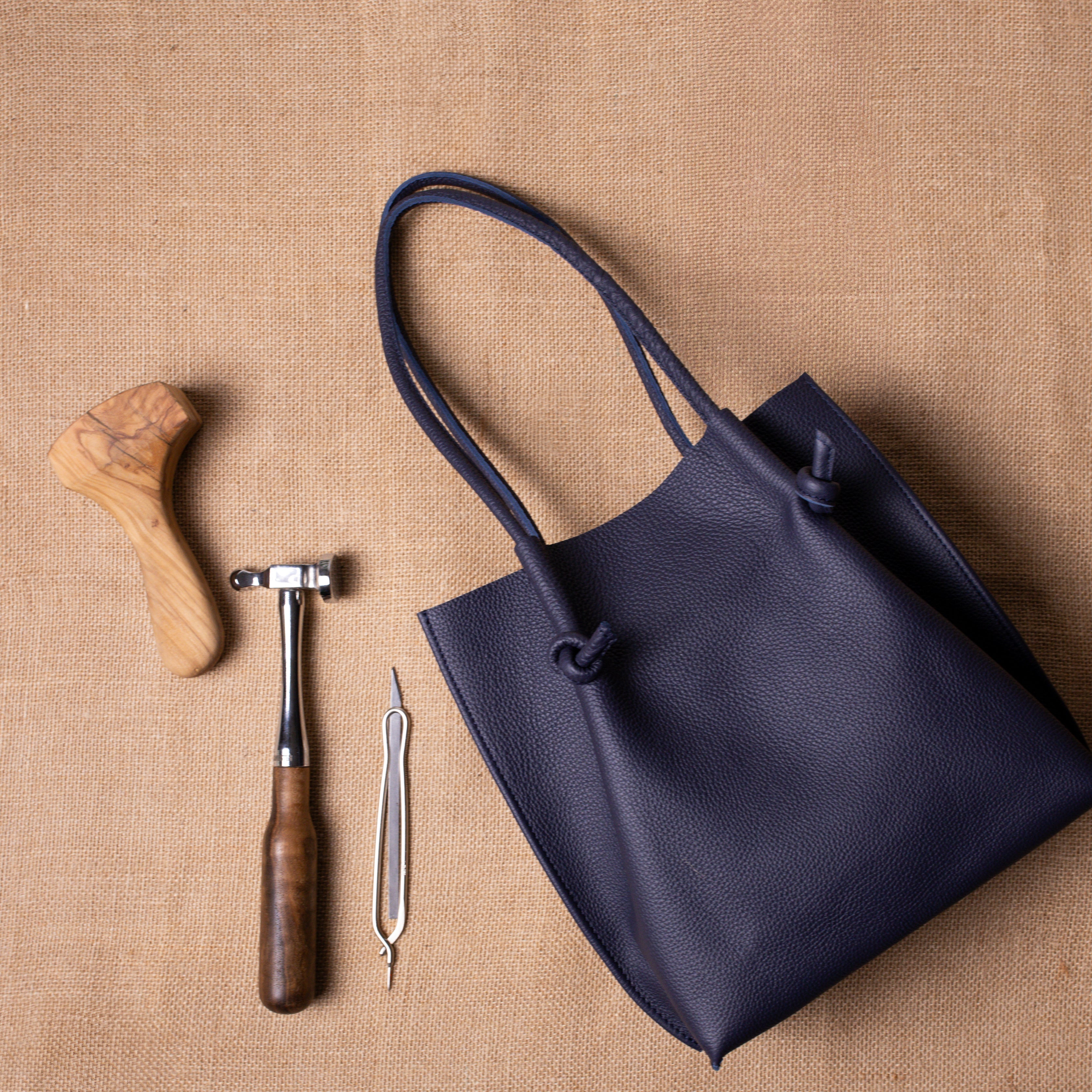 Flatlay of the Flora Leather Tote paired with artisanal tools on a burlap surface—capturing the handmade essence of Atelier PEGAI’s craftsmanship.