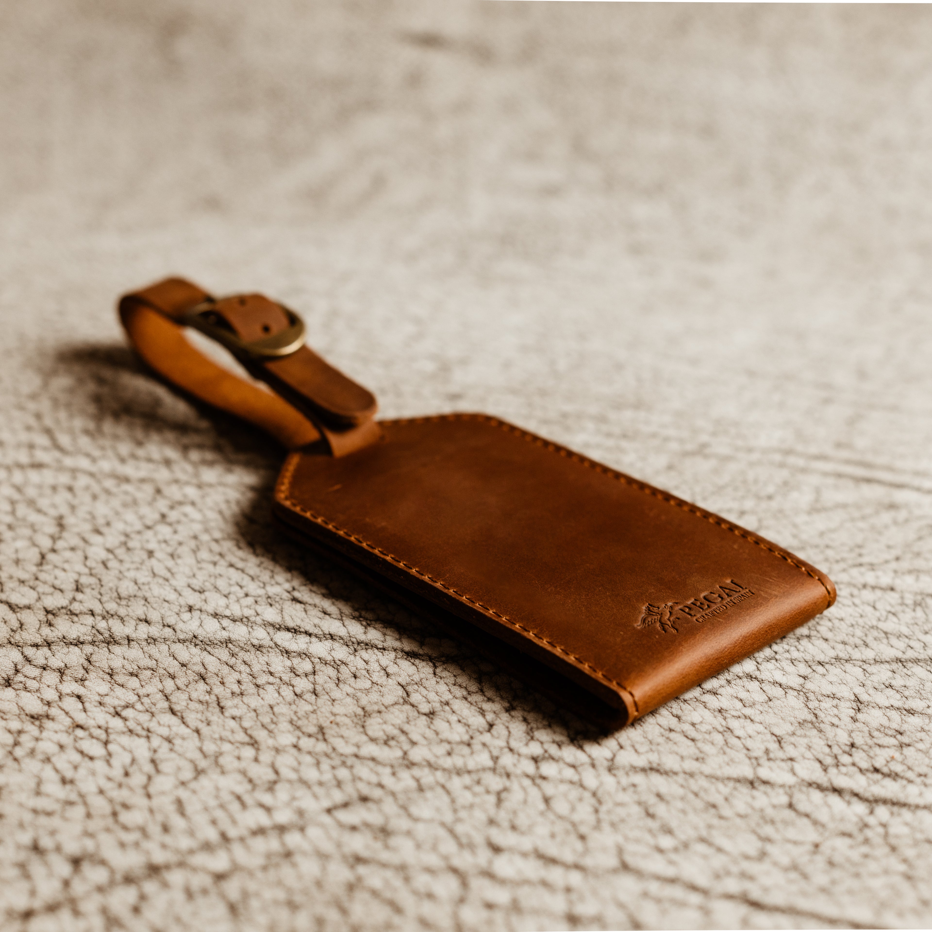 Brown leather luggage tag with antique brass hardware and rugged Crazy Horse leather finish