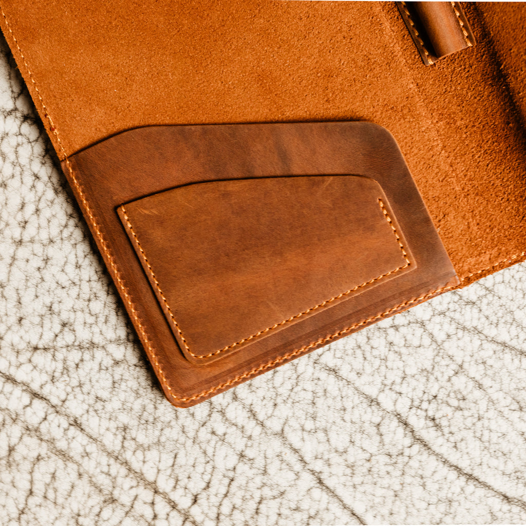 Close-up of PEGAI Eriksen Jr. padfolio interior showing the angled card slot pocket stitched in mahogany Dallas Crazy Horse leather against a warm tan suede lining.