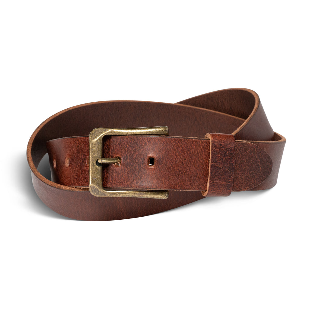 Buffalo Men's Leather Belt in Rustic Brown, coiled on a white surface. Full-grain vegetable-tanned calfskin in a warm russet brown tone with natural pull-up surface variation and subtle hide markings. Antique brass rectangular buckle with a worn, slightly mottled finish and a leather keeper loop.