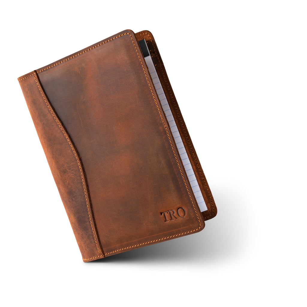 PEGAI Eriksen Jr. padfolio in mahogany Dallas Crazy Horse leather, standing closed at an angle with a lined legal pad tucked inside and embossed "TRO" monogram on the cover. 