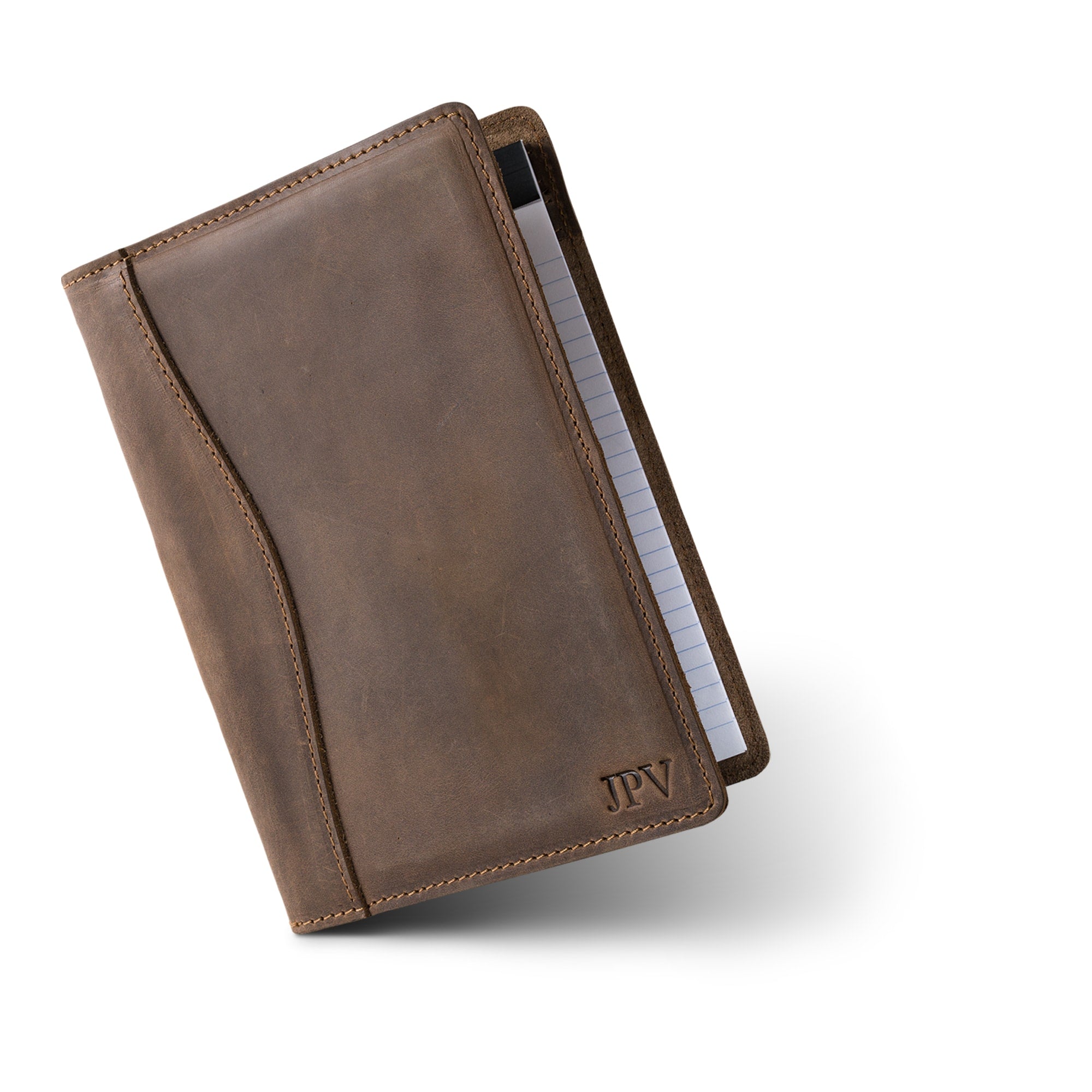 Sand Brown Eriksen padfolio tilts forward, closed, with 'JPV' initials embossed at the bottom right corner near the visible edge of the lined notepad.